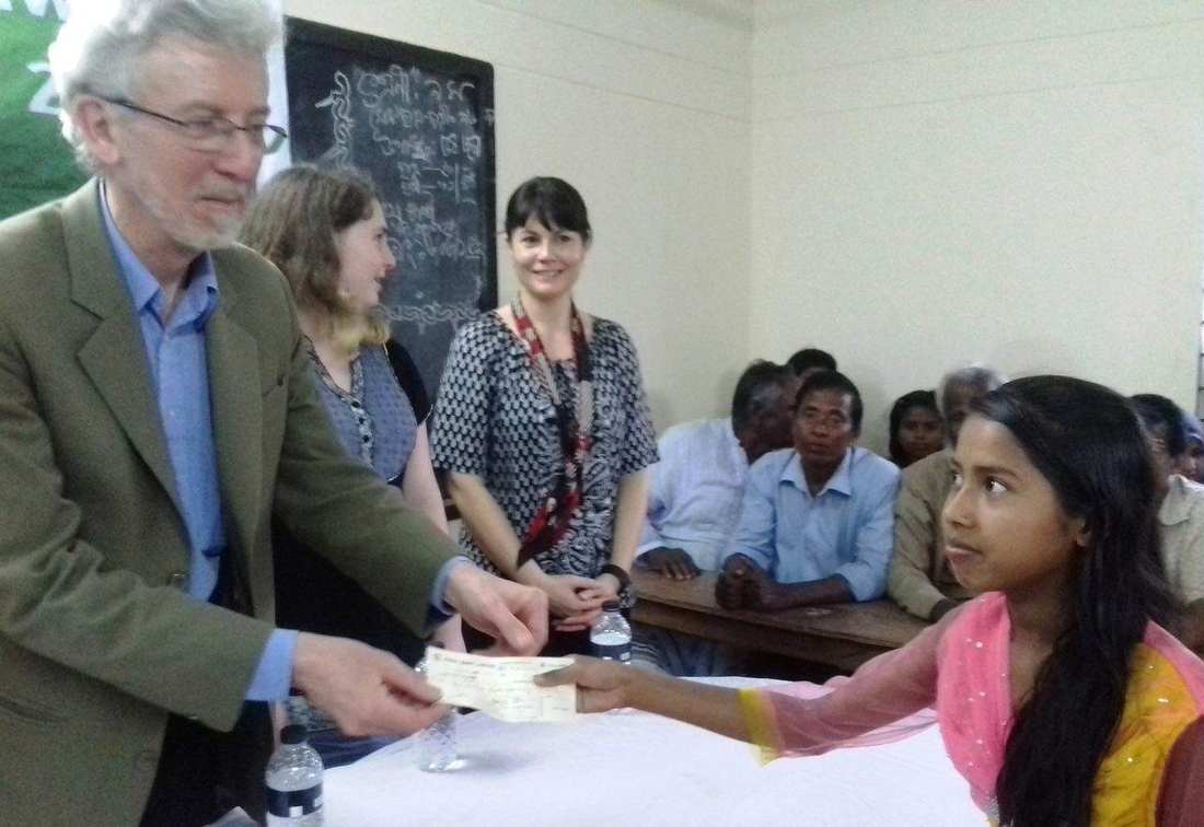 A girl receiving a scholarship cheque from an OfP supporter at a ceremony