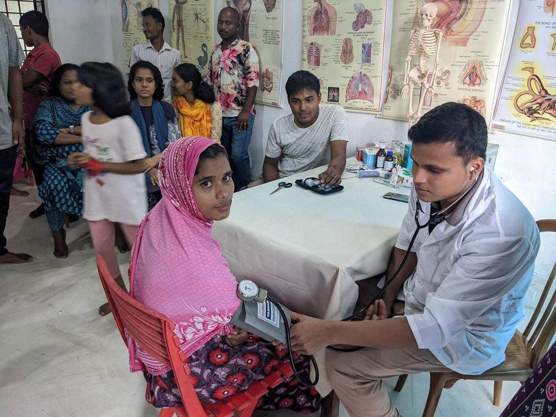 A health worker checking a woman's blood pressure at an OfP health camp