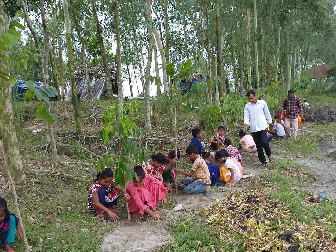 Children planting tree saplings along a village path