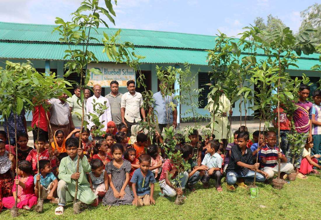 Children at OfP's Bluebell School holding tree saplings during a planting event
