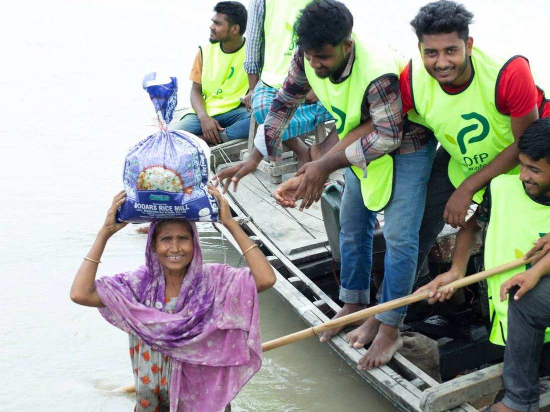 OfP volunteers handing rice relief to a resident from a boat during flooding